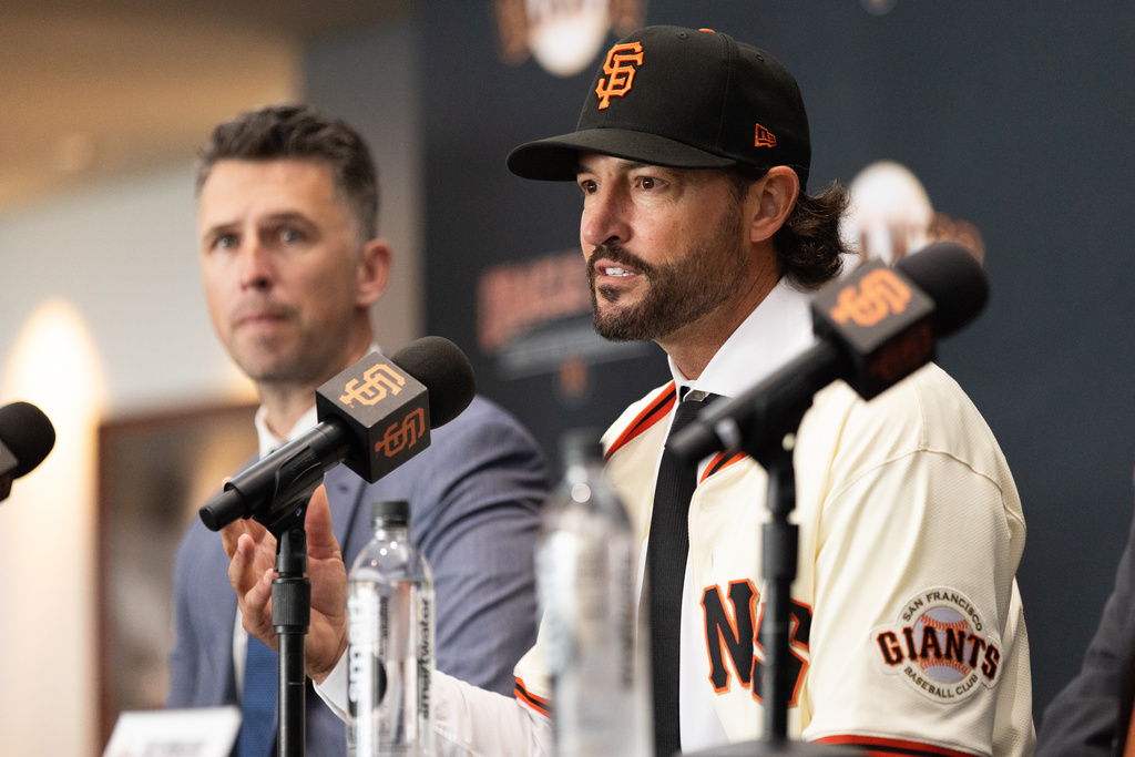 San Francisco Giants President of Baseball Operations Buster Posey, left, looks on as Tony Vitello speaks during a press conference welcoming Vitello as the new manager of the baseball team, Thursday, Oct. 30, 2025, in San Francisco. (AP Photo/Benjamin Fanjoy)