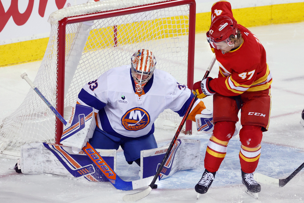 New York Islanders goalie David Rittich, left, makes a save against Calgary Flames' Connor Zary during the first period of an NHL hockey game in Calgary, Alta., Saturday, Jan. 17, 2026. (Larry MacDougal /The Canadian Press via AP)