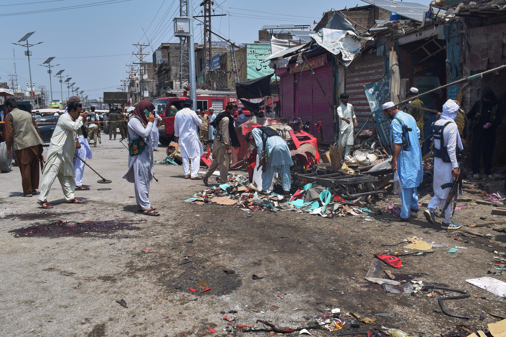 Plainclothes police officers examine damage at the site of a bomb explosion at a market in Sarai Norag in Lakki Marwat, a district in Pakistan's Khyber Pakhtunkhwa province, Tuesday, May 12, 2026. (AP Photo/G.A Marwat)