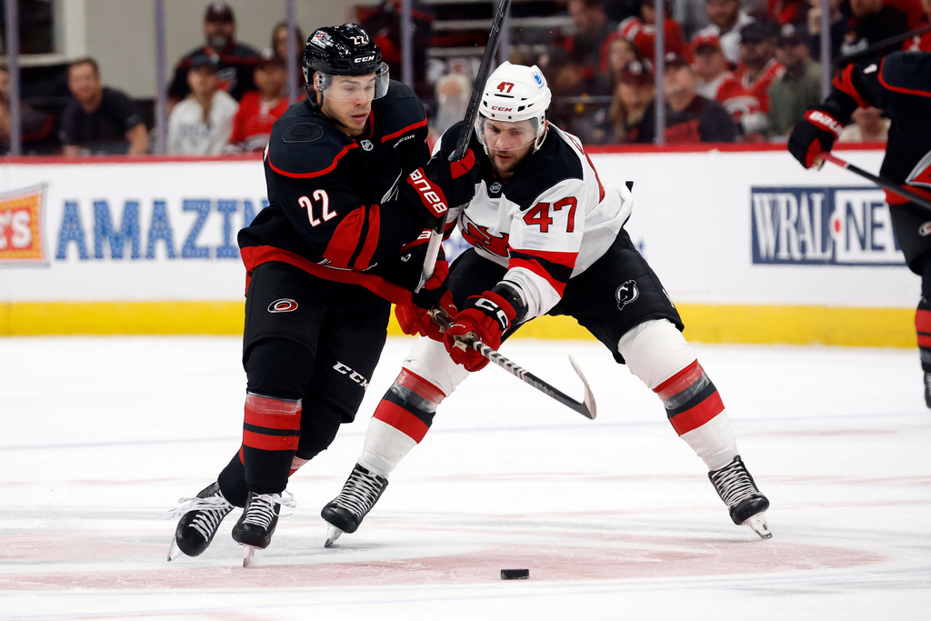 Carolina Hurricanes' Logan Stankoven (22) battles for the puck with New Jersey Devils' Paul Cotter (47) during the second period of an NHL hockey game in Raleigh, N.C., Thursday, Oct. 9, 2025. (AP Photo/Karl DeBlaker)