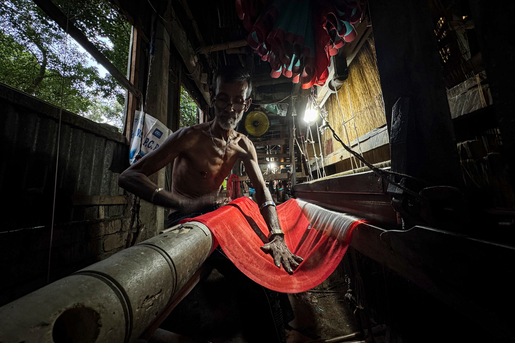 A weaver looks at the design blueprint for a Tangail saree as he operates a loom at a weaving workshop in Tangail District, Bangladesh, Nov. 5, 2025. (AP Photo/Mahmud Hossain Opu)