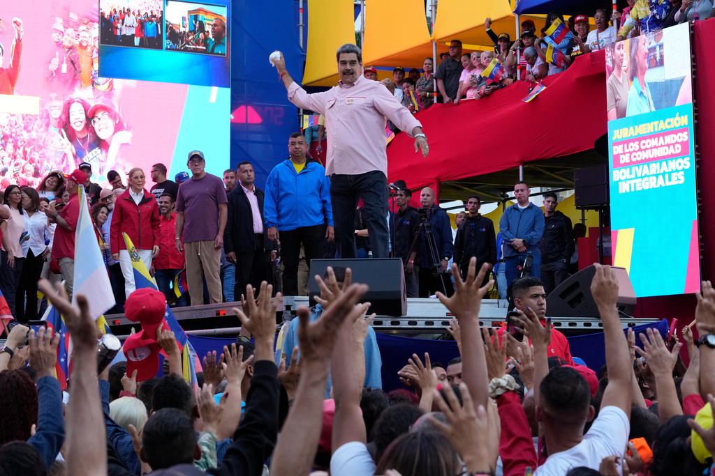 FILE - Venezuelan President Nicolas Maduro winds up to throw his handkerchief to supporters during a swearing-in event for government-organized community committees at the presidential palace in Caracas, Venezuela, Dec. 1, 2025. (AP Photo/Ariana Cubillos, File)
