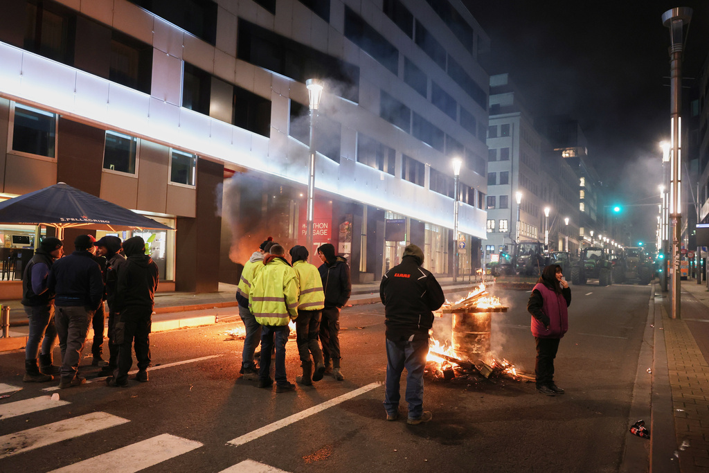 Protestors and farmers stand next to a wood fire during a demonstration outside the EU Summit in Brussels, Thursday, Dec. 18, 2025. (AP Photo/Omar Havana)