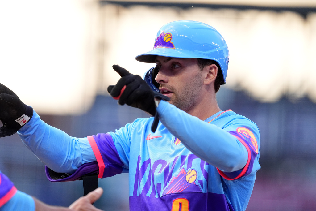 Colorado Rockies' Edouard Julien gestures to the dugout after reaching first base on an RBI single off Milwaukee Brewers starting pitcher Brandon Sproat in the second inning of a baseball game Friday, June 5, 2026, in Denver. (AP Photo/David Zalubowski)