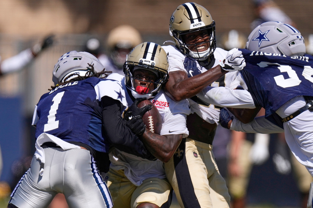 New Orleans Saints running back Travis Etienne, second from left, tries to get by Dallas Cowboys safety P.J. Locke, left, as wide receiver Kevin Austin Jr., second from right, and safety Jalen Thompson battle during an NFL football joint practice, Tuesday, Aug. 18, 2026, in Oxnard, Calif. (AP Photo/Mark J. Terrill)