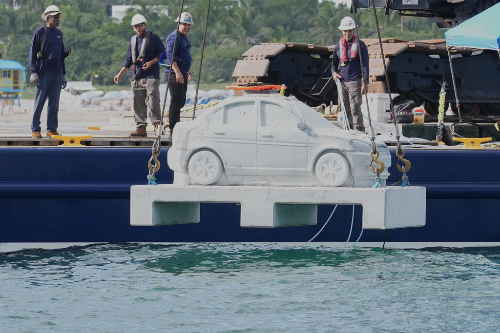 Workers prepare to submerge a marine grade concrete car that will be attached with native corals as part of a underwater marine sculpture park off South Beach Tuesday, Oct. 28, 2025, in Miami Beach, Fla. (AP Photo/Marta Lavandier)