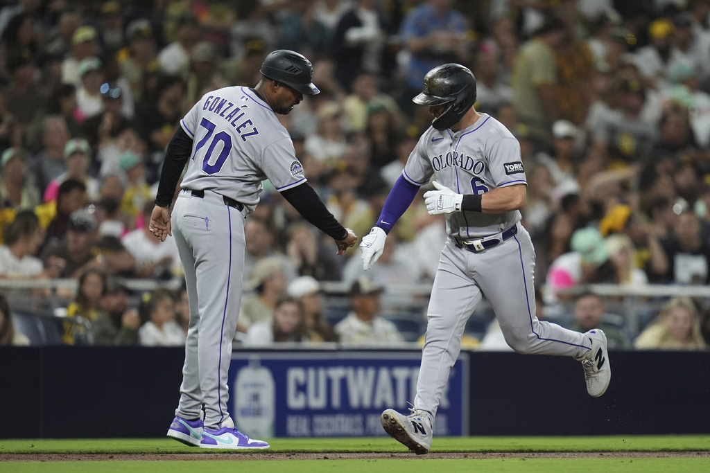 Colorado Rockies' Kyle Farmer, right, celebrates with third base coach Andy González after hitting a home run during the fourth inning of a baseball game against the San Diego Padres Friday, Sept. 12, 2025, in San Diego. (AP Photo/Gregory Bull)