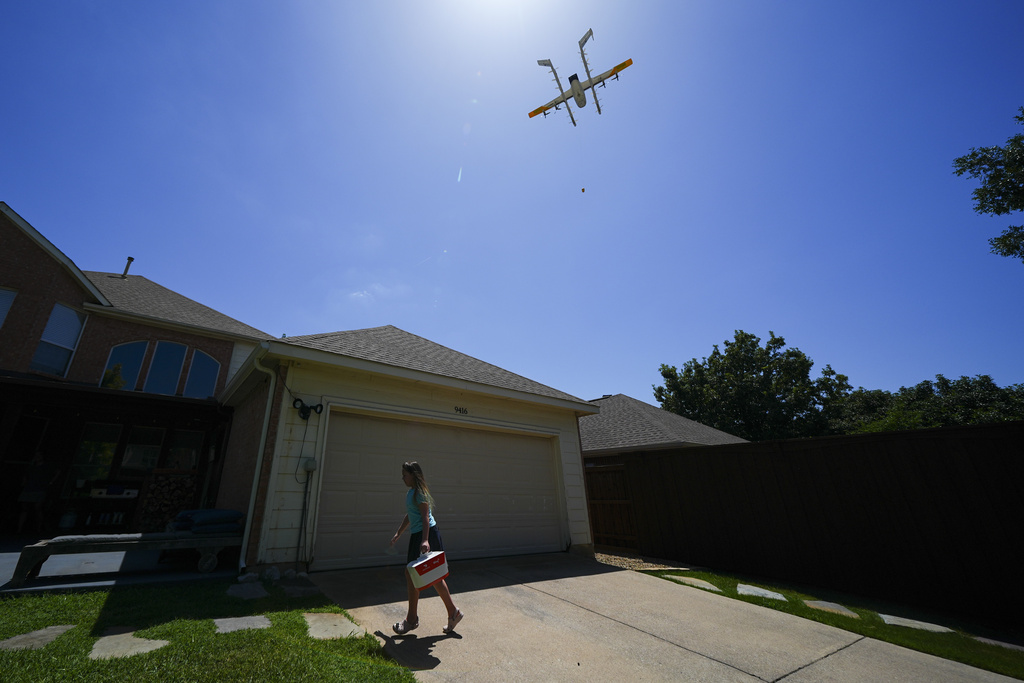 Julep Toth, 9, carries a package delivered to her house via a drone, Thursday, July 31, 2025, in Frisco, Texas. (AP Photo/Julio Cortez)