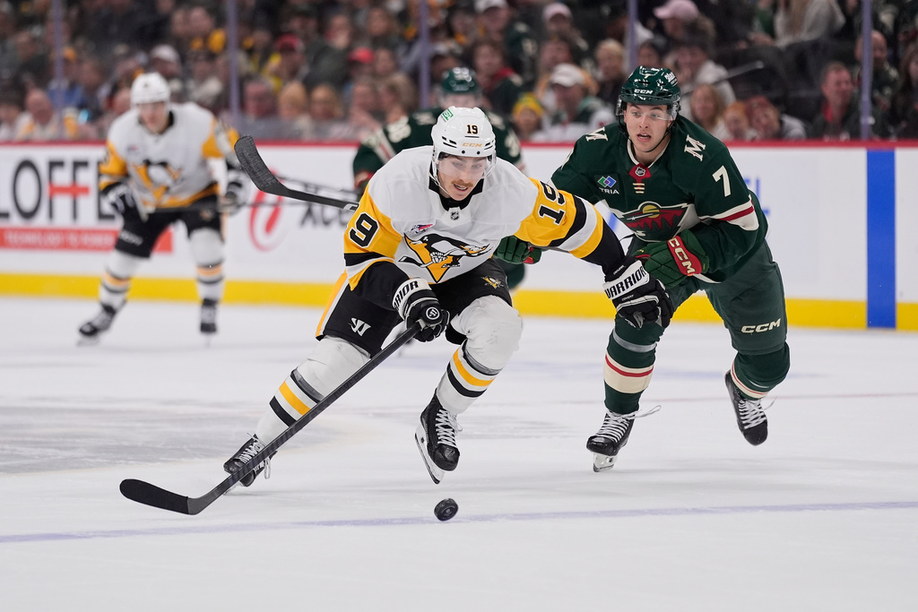 Pittsburgh Penguins center Connor Dewar (19) skates with the puck as Minnesota Wild defenseman Brock Faber (7) defends during the second period of an NHL hockey game, Thursday, Oct. 30, 2025, in St. Paul, Minn. (AP Photo/Abbie Parr)