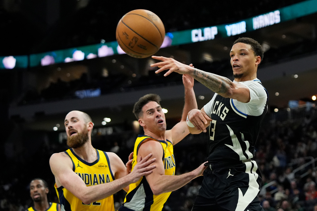 Milwaukee Bucks' Ryan Rollins, right, passes around Indiana Pacers' T.J. McConnell, center, and Jay Huff during the second half of an NBA basketball game, Sunday, March 15, 2026, in Milwaukee. (AP Photo/Aaron Gash)