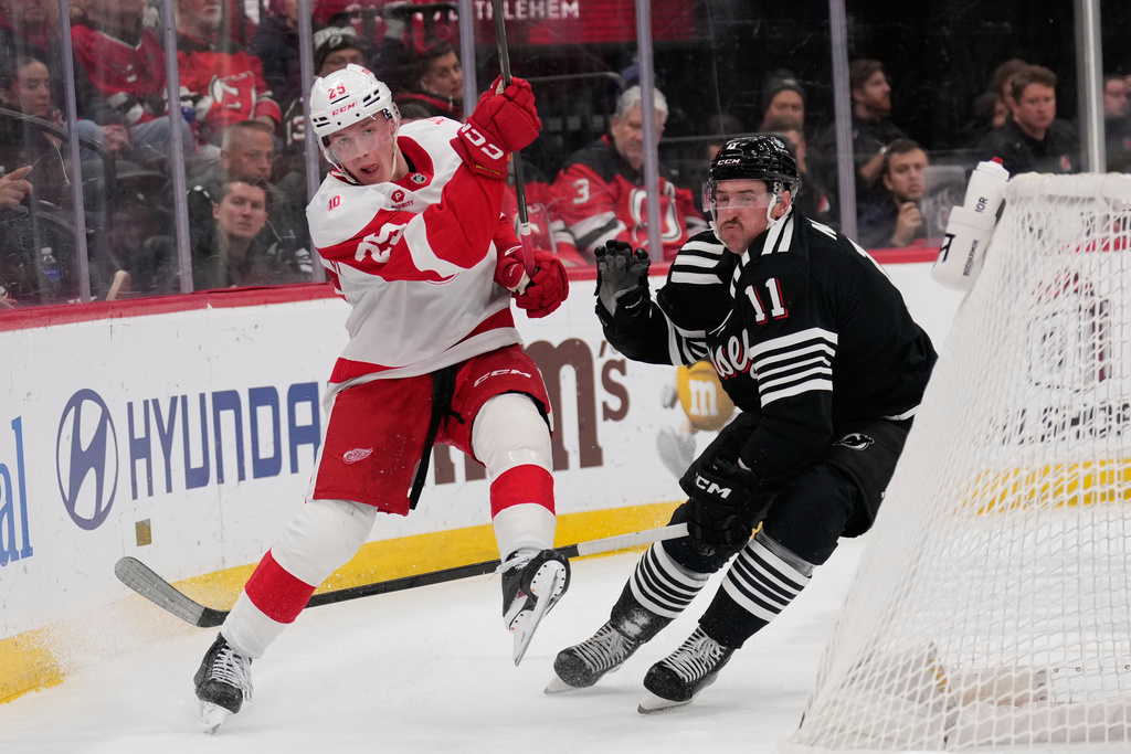 Detroit Red Wings' Jacob Bernard-Docker, left, gets the puck away from New Jersey Devils' Stefan Noesen during the second period of an NHL hockey game in Newark, N.J., Monday, Nov. 24, 2025. (AP Photo/Seth Wenig)