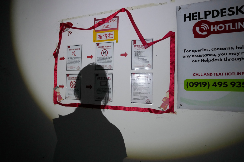 A journalist checks signs inside an abandoned residential building at the sprawling former Baofu scam compound that was raided by authorities last year in Bamban, Tarlac city, northern Philippines, Thursday, June 5, 2025. (AP Photo/Aaron Favila)