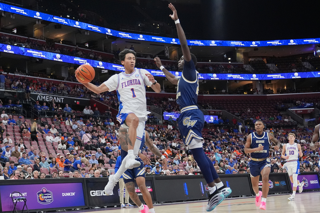 Florida guard Xaivian Lee (1) passes the ball as George Washington forward Tyrone Marshall Jr., right, defends during the second half of an NCAA college basketball game at the Orange Bowl Basketball Classic, Saturday, Dec. 13, 2025, in Sunrise, Fla. (AP Photo/Lynne Sladky)