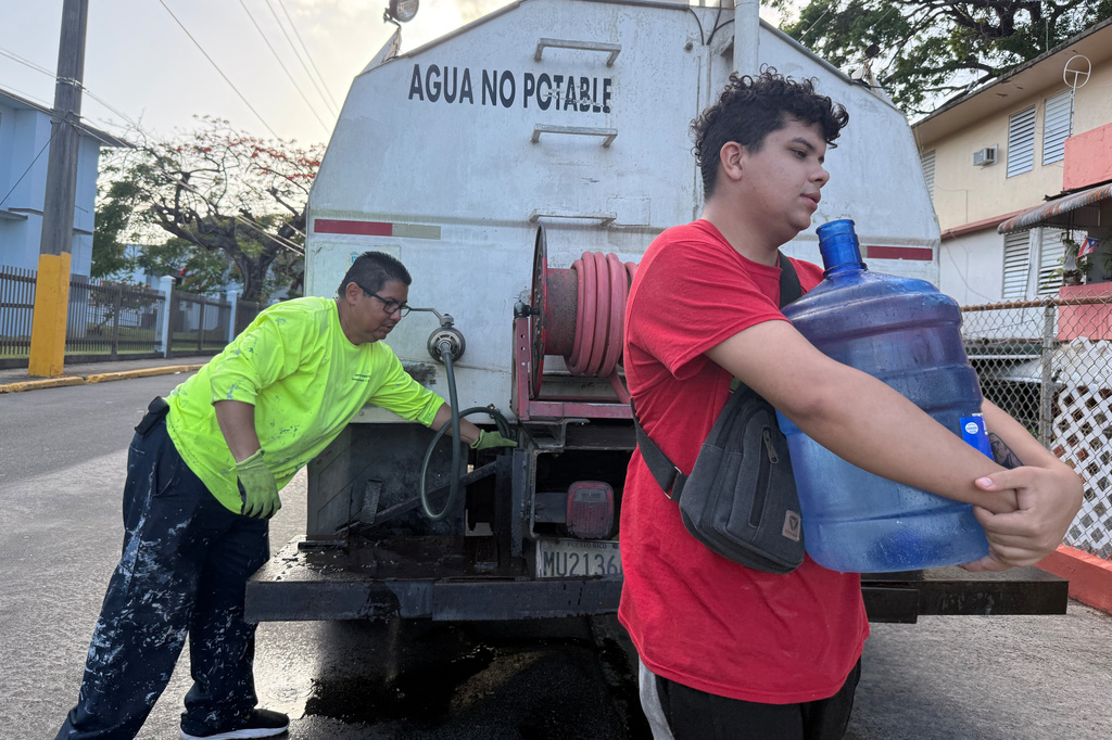 Bryan Pérez hauls a five-gallon water jug to his apartment in the Villa Kennedy public housing complex in San Juan, Puerto Rico, Wednesday, June 10, 2026. (AP Photo/Danica Coto)