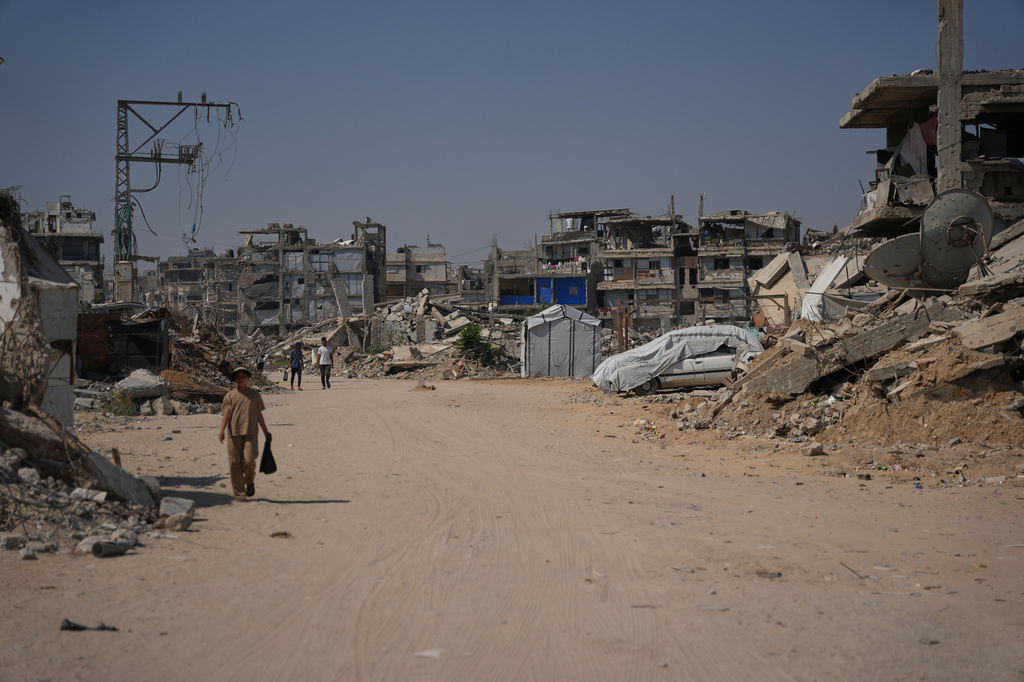Palestinian walk by the rubble of buildings that were destroyed during the Israel Hamas war, in Khan Younis, southern Gaza Strip, Friday, July 31, 2026. (AP Photo/Abdel Kareem Hana)