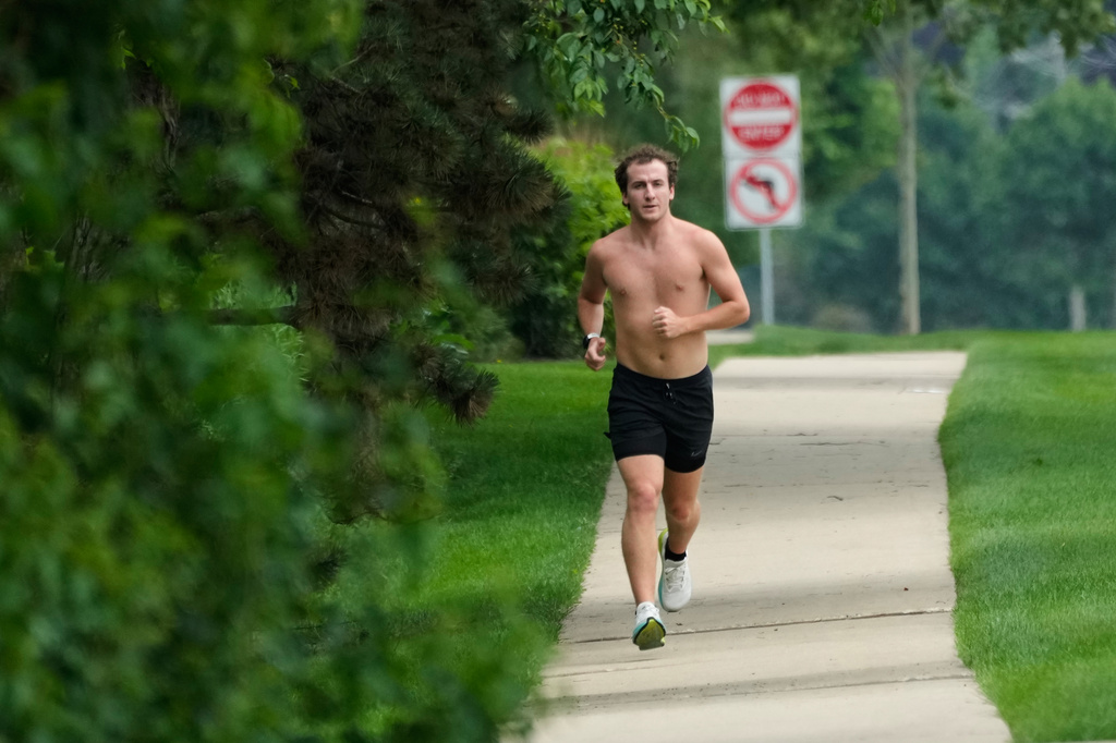 A jogger runs on the street during a hot weather day in Mount Prospect, Ill., Monday, June 29, 2026. (AP Photo/Nam Y. Huh)