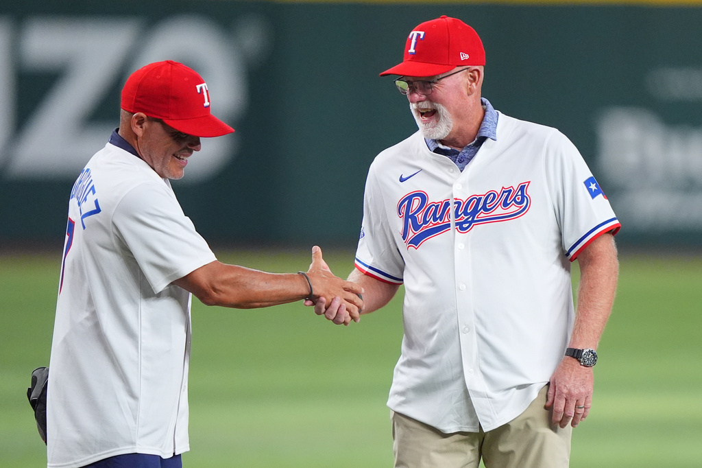 Former Texas Rangers Ivan Rodriguez, left, and Rusty Greer shake hands before a baseball game between the Los Angeles Angels and Texas Rangers, Saturday, Aug. 22, 2026, in Arlington, Texas. (AP Photo/LM Otero)