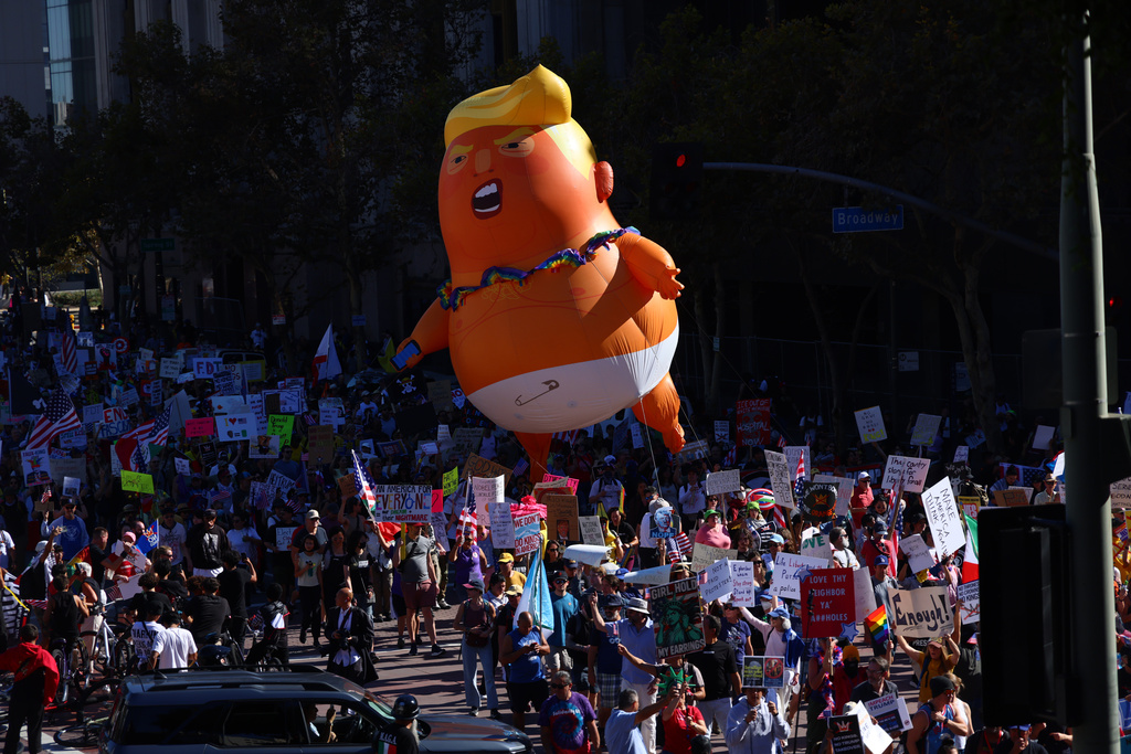 Pulling a giant inflatable Donald Trump protesters march in the streets during a "No Kings" protest Saturday, Oct. 18, 2025, in Los Angeles. (AP Photo/Ethan Swope)