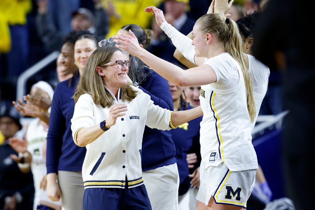 Michigan guard Olivia Olson, right, and coach Kim Barnes Arico, left, embrace in the closing moments of their win over North Carolina State in the second round of the NCAA college basketball tournament, Sunday, March 22, 2026, in Ann Arbor, Mich. (AP Photo/Al Goldis)