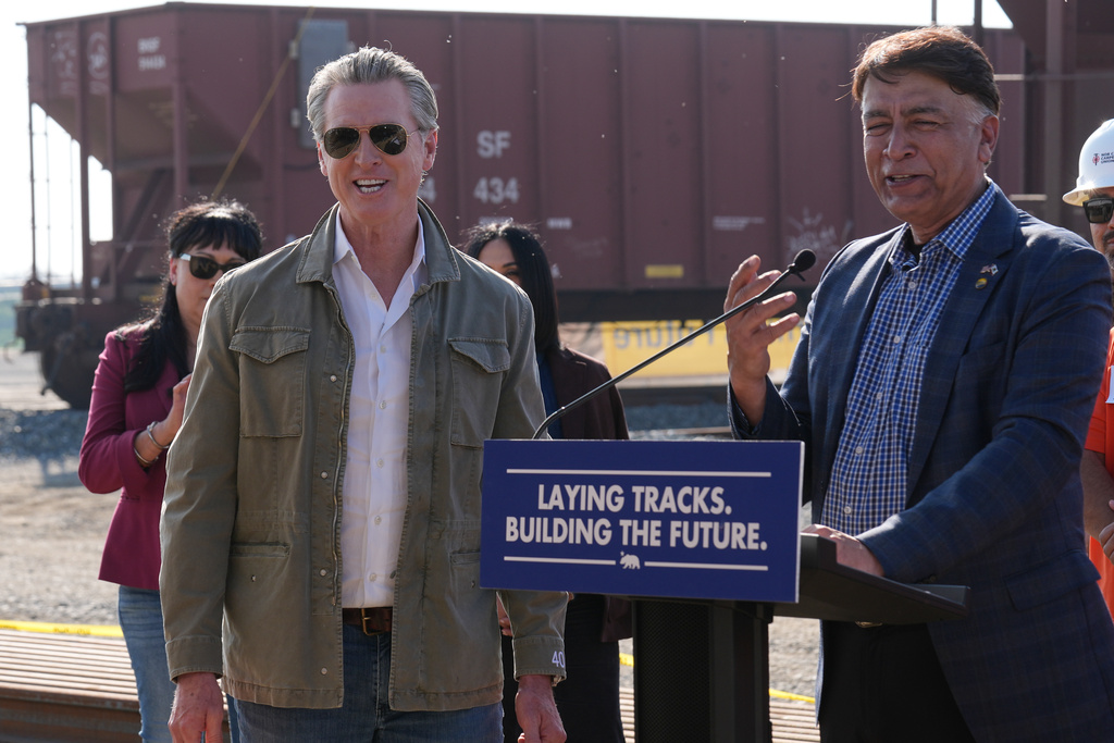 High‑Speed Rail Authority CEO Ian Choudri, right, speaks during a news conference accompanied by California Gov. Gavin Newsom, left, at the California High‑Speed Rail Authority 150-acre Southern Railhead site in the Wasco/Shafter area as the first step in bringing in materials, starting track installation between Merced and Bakersfield, in Wasco, Calif., Tuesday, Feb.3, 2026. (AP Photo/Damian Dovarganes)
