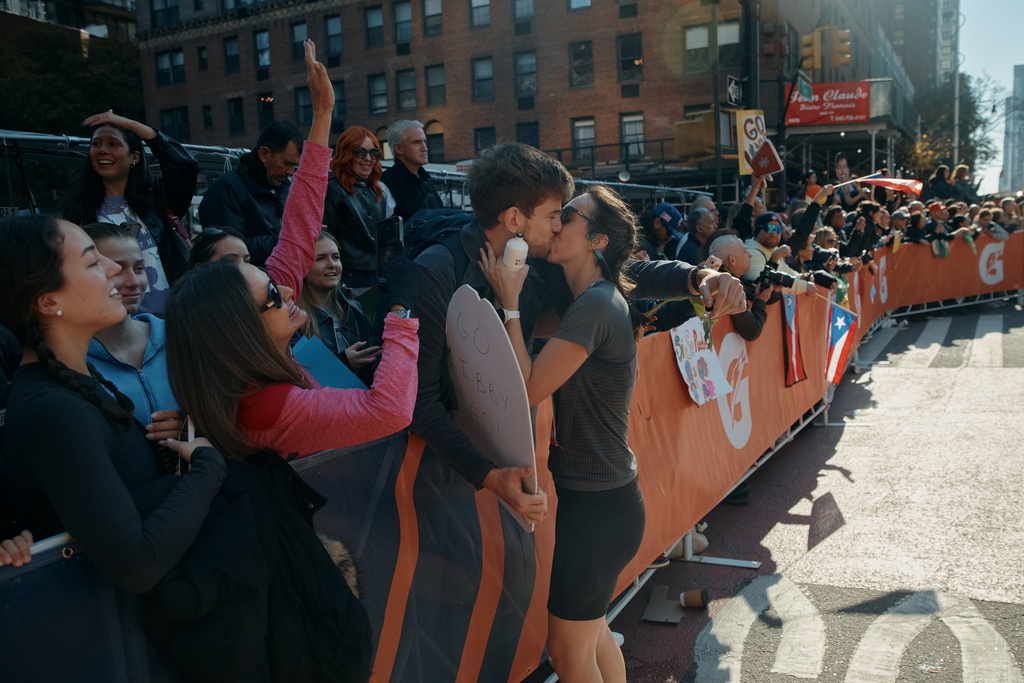 A runner takes a break to kiss her partner during the New York City Marathon in New York, Sunday, Nov. 2, 2025. (AP Photo/Andres Kudacki)