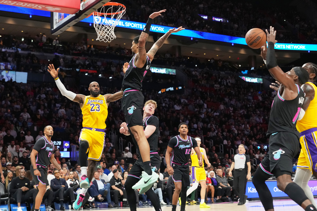 Los Angeles Lakers forward LeBron James (23) attempts to pass as Miami Heat center Bam Adebayo, right, goes for the ball during the first half of an NBA basketball game, Thursday, March 19, 2026, in Miami. (AP Photo/Lynne Sladky)