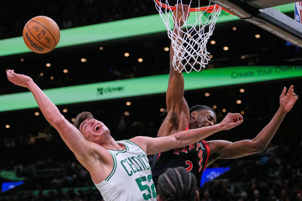 Boston Celtics center Luka Garza (52) battles for a rebound against Toronto Raptors forward Jonathan Mogbo (2) during the first half of an NBA basketball game Friday, Jan. 9, 2026, in Boston. (AP Photo/Charles Krupa)