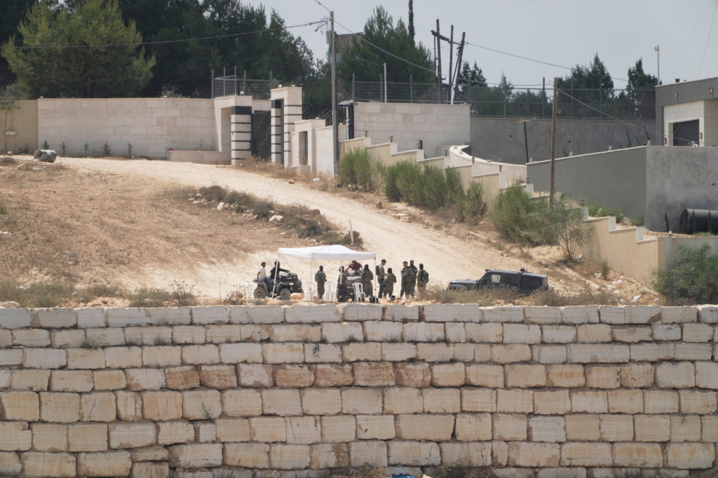 Israeli settlers patrol a road in front of besieged Palestinian houses, in the occupied West Bank village of Qusra, south of Nablus, Monday, Aug. 17, 2026. (AP Photo/Majdi Mohammed)