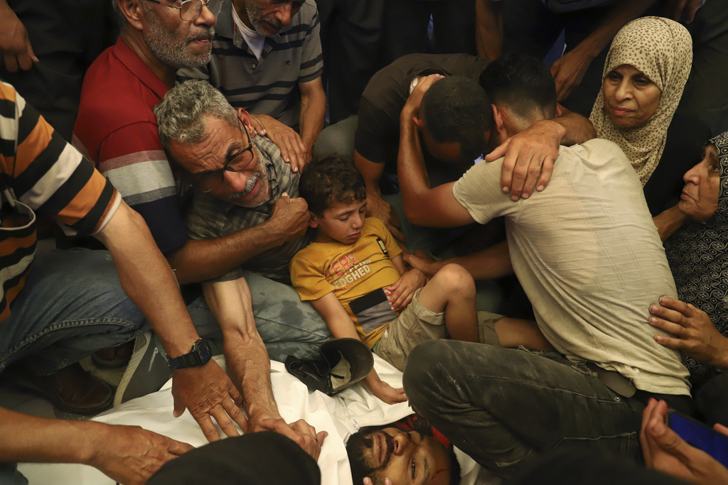FILE - Ata Qasas, center left, mourns over the body of his son Rashad Qasas, who was killed while heading to an aid distribution hub, during his funeral in Rafah, southern Gaza Strip, Wednesday, June 11, 2025. (AP Photo/Mariam Dagga, File)
