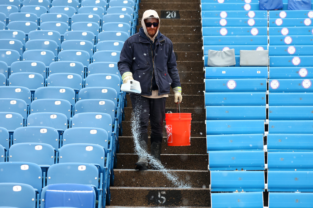 FILE - Salt is applied to the steps as snow falls at Buffalo Bills Highmark Stadium before an NFL football game between the Buffalo Bills and the Cincinnati Bengals, Dec. 7, 2025, in Orchard Park, N.Y. (AP Photo/Jeffrey T. Barnes, File)