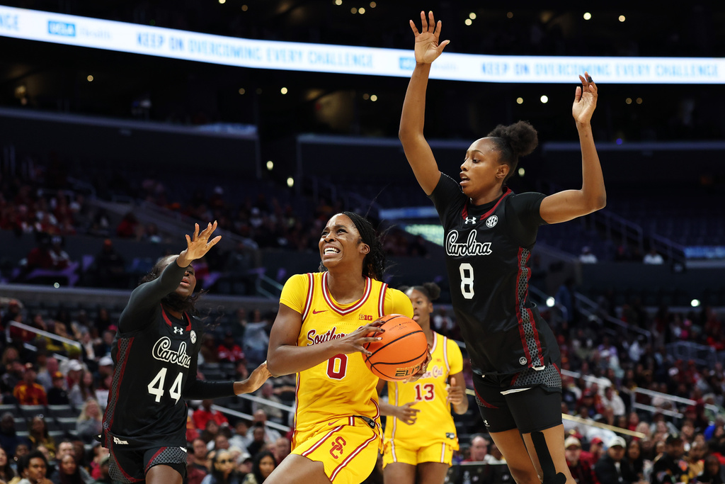 Southern California forward Zora Fray-Chinn (0) drives the ball to the basket against South Carolina guard Agot Makeer (44) and South Carolina forward Joyce Edwards (80 during the first half of an NCAA college basketball game Saturday, Nov. 15, 2025, in Los Angeles. (AP Photo/Allison Dinner)