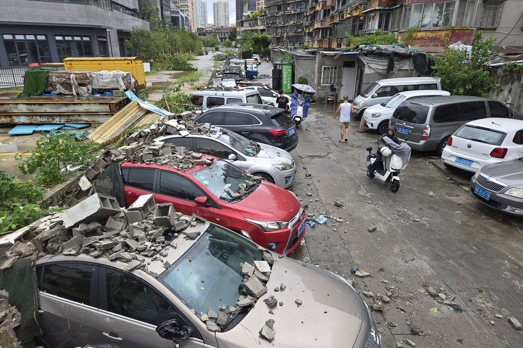 Residents pass by vehicles damaged by a fallen wall in the aftermath of Typhoon Dolphin in Wenzhou in eastern China's Zhejiang province, Monday, Aug. 10, 2026. (Chinatopix via AP)