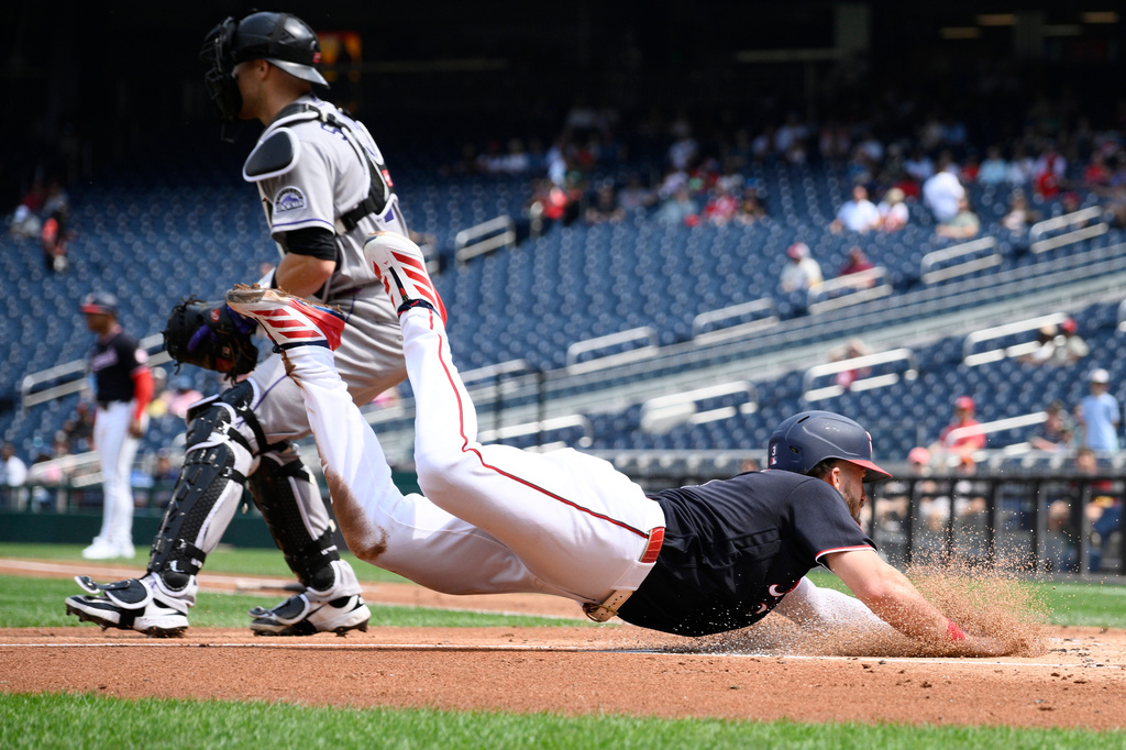 Washington Nationals' Dylan Crews, front, slides home to score on a sacrifice fly by Brady House during the first inning of a baseball game as Colorado Rockies catcher Brett Sullivan waits for the throw, Thursday, Aug. 27, 2026, in Washington. (AP Photo/Nick Wass)