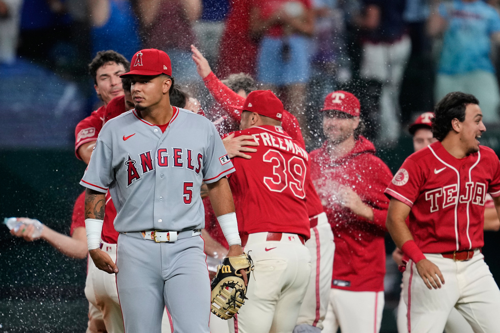 Los Angeles Angels left fielder Vaughn Grissom (5) walks away as the Texas Rangers celebrate a run-scoring single by Ezequiel Duran in the 10th inning of a baseball game Friday, Aug. 21, 2026, in Arlington, Texas. (AP Photo/Tony Gutierrez)