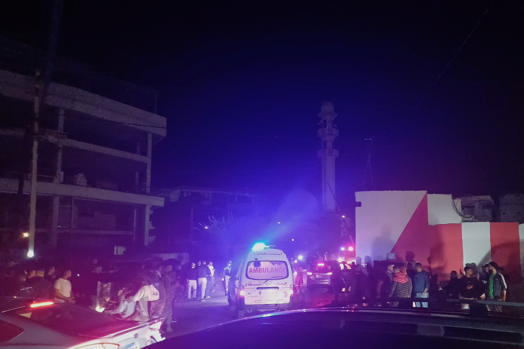 People gathering next of an ambulance as it enters the Ein el-Hilweh refugee camp in the southern port city of Sidon, Lebanon, Tuesday, Nov. 18, 2025. (AP Photo/Mohammed Zaatari)