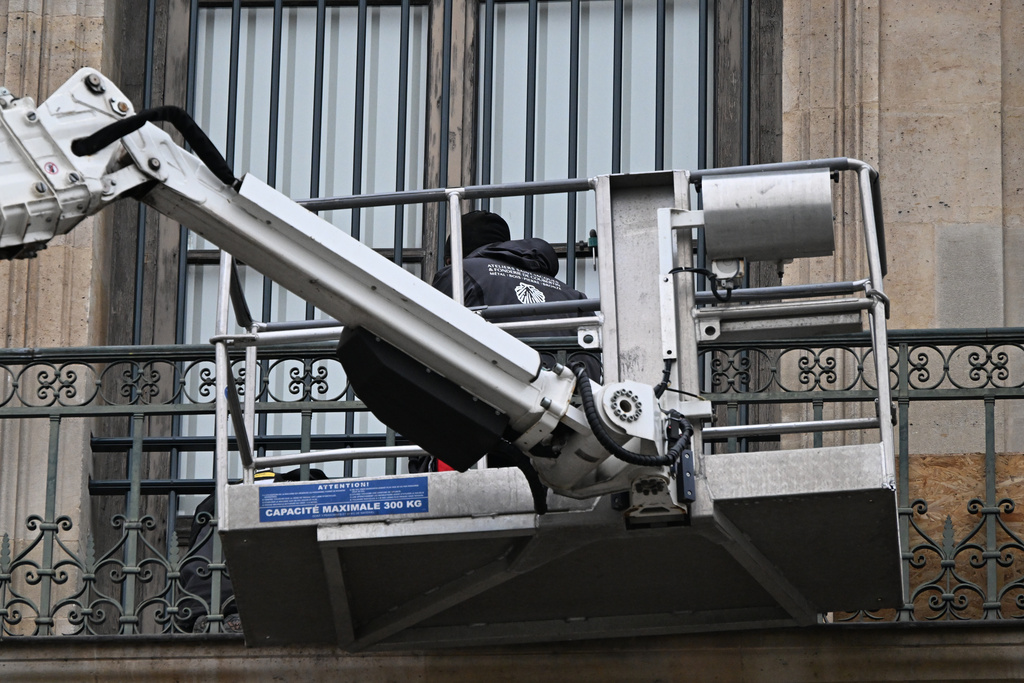Workers install metal security bars over the window where thieves broke into the Louvre museum on Oct.19, Tuesday Dec.23, 2025 in Paris. (AP Photo/Emma Da Silva)
