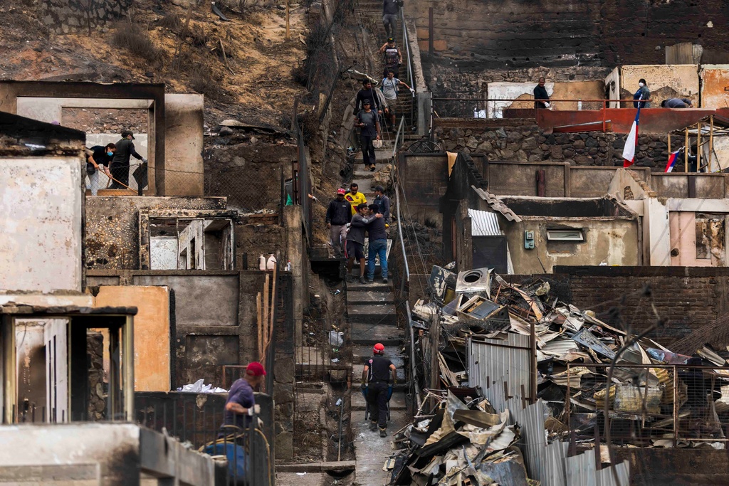 People salvage belongings from their homes that were damaged by wildfires in Lirquen, Chile, Tuesday, Jan. 20, 2026. (AP Photo/Javier Torres)