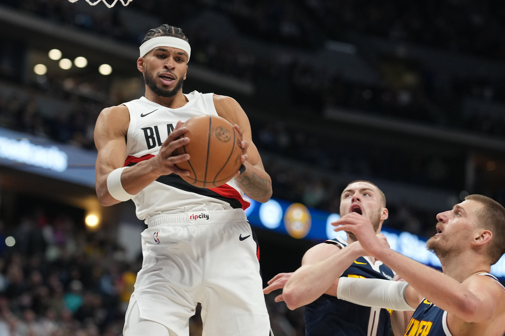 Portland Trail Blazers forward Toumani Camara left, pulls in a rebound as Denver Nuggets guard Christian Braun, center, and center Nikola Jokic, right, defend in the first half of an NBA basketball game Monday, April 6, 2026, in Denver. (AP Photo/David Zalubowski)