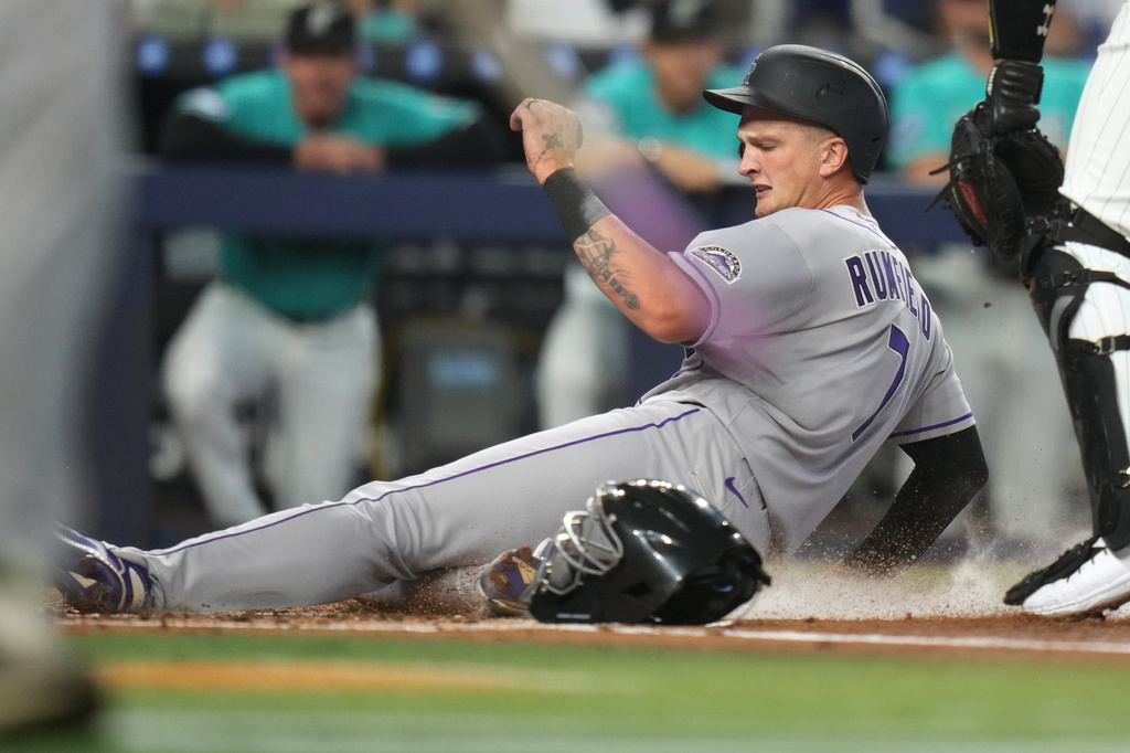 Colorado Rockies' TJ Rumfield (7) scores on a double hit by Jordan Beck during the first inning of a baseball game against the Miami Marlins, Sunday, March 29, 2026, in Miami. (AP Photo/Lynne Sladky)
