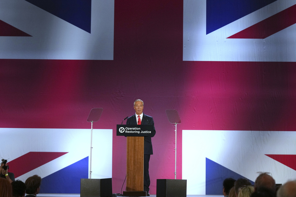 British Reform party leader Nigel Farage addresses journalists during a press conference in a hangar at Oxford Airport in Kidlington, England, Tuesday, Aug. 26, 2025.(AP Photo/Joanna Chan)