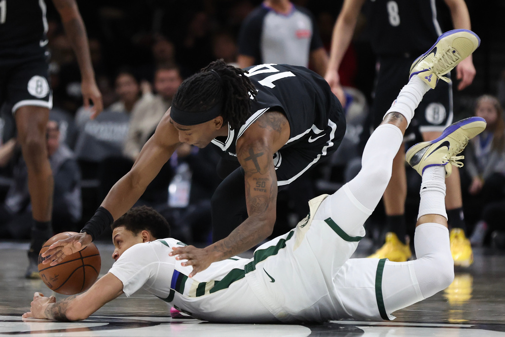 Milwaukee Bucks guard Ryan Rollins and Brooklyn Nets guard Terance Mann (14) battle for a loose ball during the first half of an NBA basketball game, Sunday, Dec. 14, 2025, in New York. (AP Photo/Heather Khalifa)