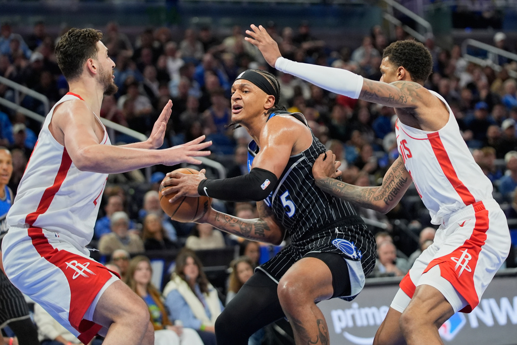 Orlando Magic forward Paolo Banchero (5) makes a move to the basket agate goes between Houston Rockets center Alperen Sengun, left, and forward Jabari Smith Jr., right, during the first half of an NBA basketball game, Thursday, Feb. 26, 2026, in Orlando, Fla. (AP Photo/John Raoux)