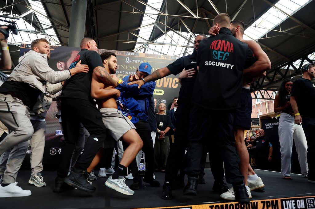 Boxers Filip Hrgovic, right, and Moses Itauma, center, are separated after Hrgovic slapped Itauma during the weigh-in, Friday, Aug. 28, 2026, in London, ahead of their IBF heavyweight championship bout. (Steven Paston/PA via AP)