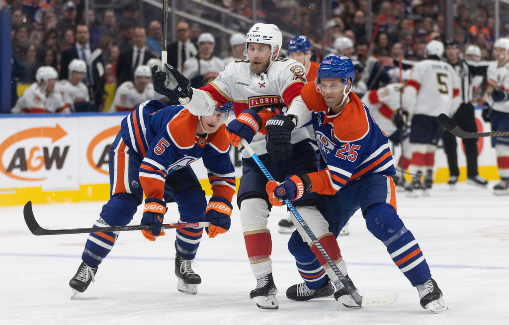 Florida Panthers' Sam Bennett (9) is checked by Edmonton Oilers' Connor Murphy (5) and Darnell Nurse (25) during third period NHL action, in Edmonton on Thursday March 19, 2026. (Jason Franson/The Canadian Press via AP)