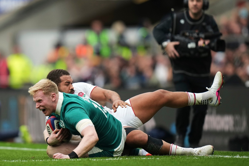 Ireland's Jamie Osborne, front, is tackled by England's Ollie Lawrence during the Six Nations rugby union match between England and Ireland in London, England, Saturday, Feb. 21, 2026. (AP Photo/Alastair Grant)