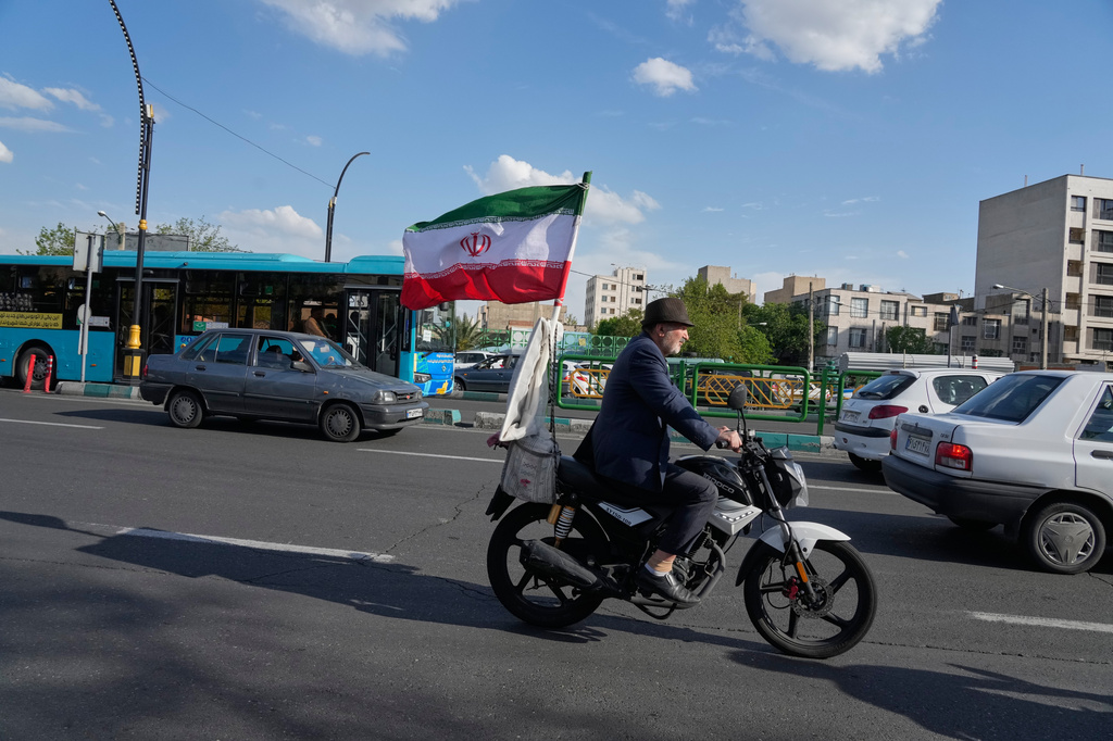 A man rides his motorbike that is adorned with an Iranian national flag, in southern Tehran, Iran, Tuesday, April 21, 2026. (AP Photo/Vahid Salemi)