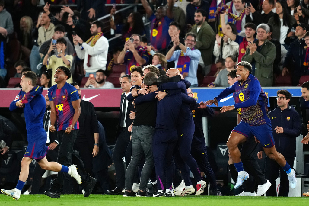 Barcelona head coach Hansi Flick, center, is embraced by his staff celebrating after defeating Real Madrid 2-0 to win the Spanish La Liga soccer championship with three rounds to spare, in Barcelona, Spain, Sunday, May 10, 2026. (AP Photo/Joan Mateu Parra)