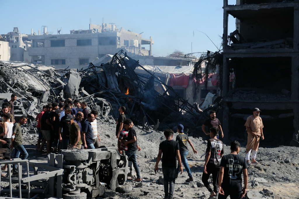 Palestinians gather around the site of an Israeli military drone strike on a blacksmith shop in Gaza City's Sabra neighborhood killing at least four Palestinians and wounded another, according to officials at Shifa hospital, where the casualties were taken on Sunday, July 12, 2026. (AP Photo/Jehad Alshrafi)