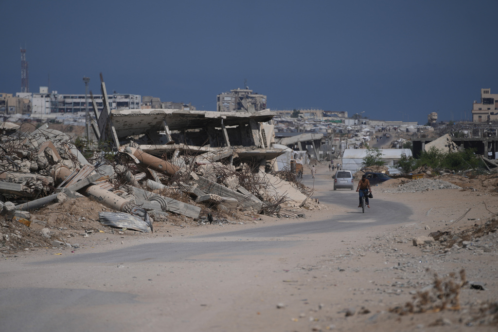 A Palestinian man rides his bicycle by the rubble of buildings that were destroyed during the Israel Hamas war, in Khan Younis, southern Gaza Strip, Friday, July 31, 2026. (AP Photo/Abdel Kareem Hana)