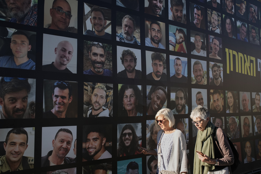 Women walk past a banner with photographs of hostages who were kidnapped and held by Hamas in the Gaza Strip, in Jerusalem, Tuesday, Oct. 7, 2025, on the second anniversary of Hamas' cross-border attack on Israel on Oct. 7, 2023, which sparked the ongoing war in Gaza. (AP Photo/Leo Correa)